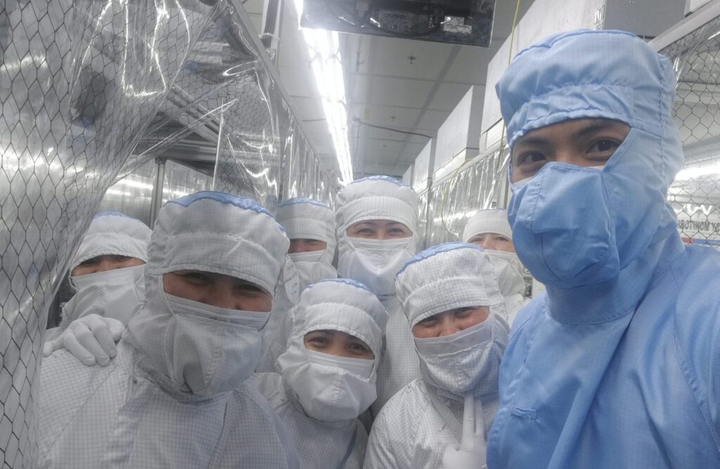 防塵服を着て製造現場に集まるチーム